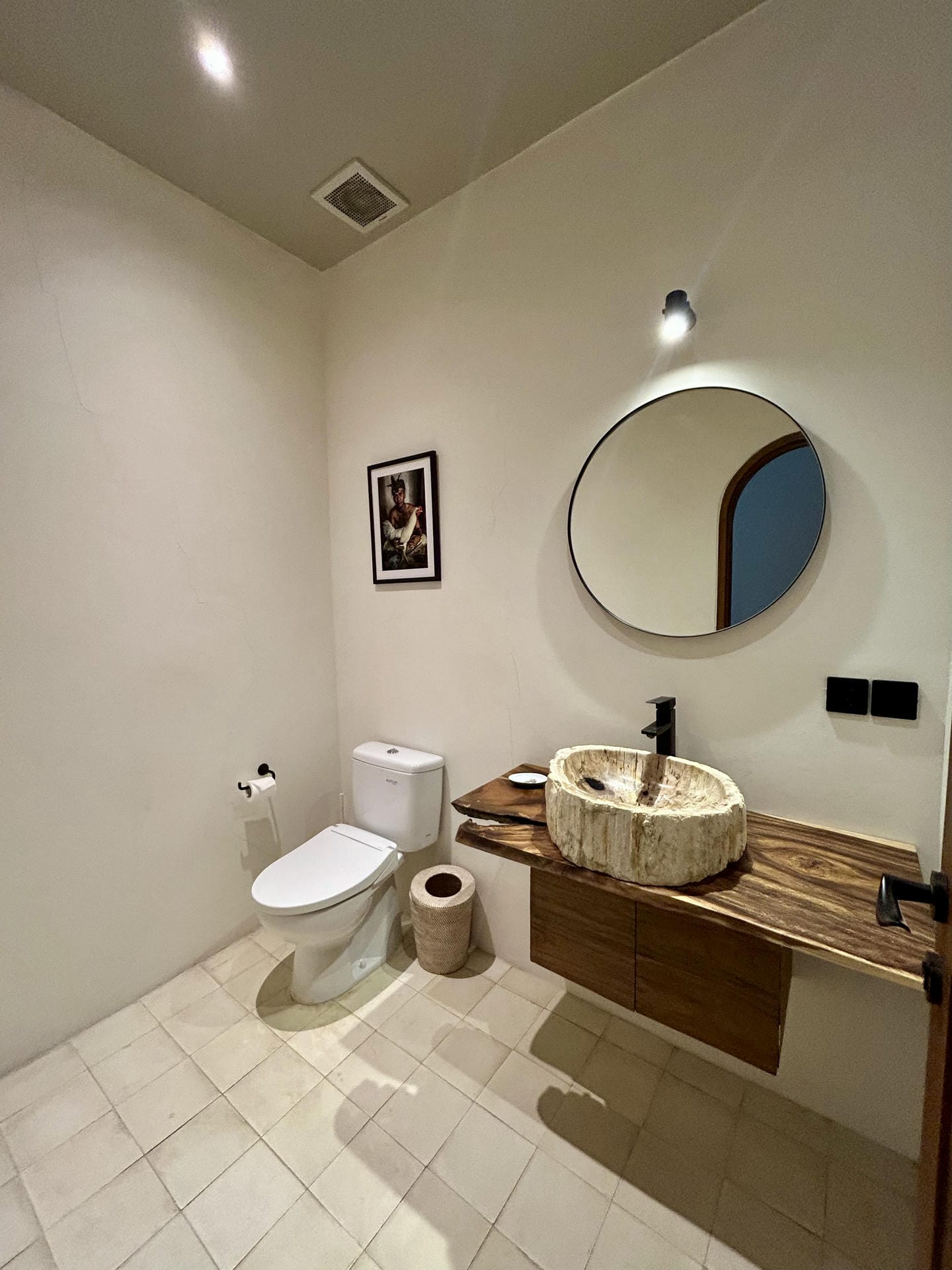 Modern bathroom with round mirror and stone sink.