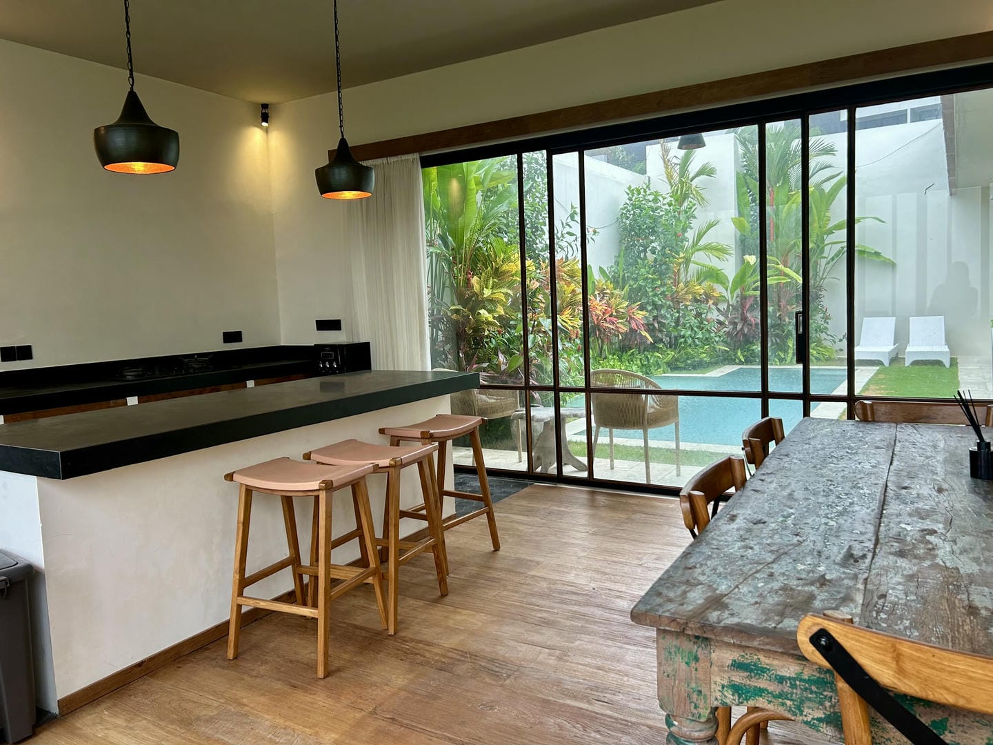Modern kitchen with pool view and wooden furniture.