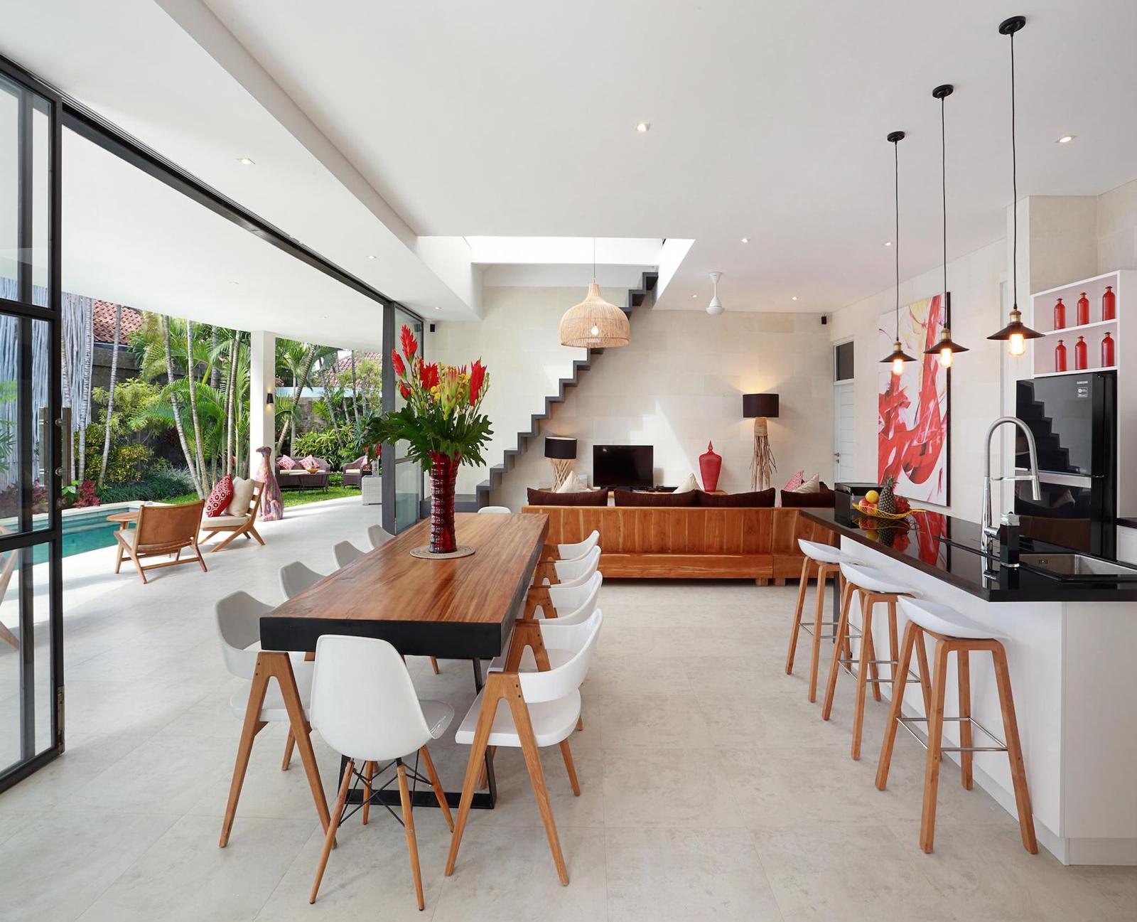 Modern open-plan living room with kitchen and pool view.