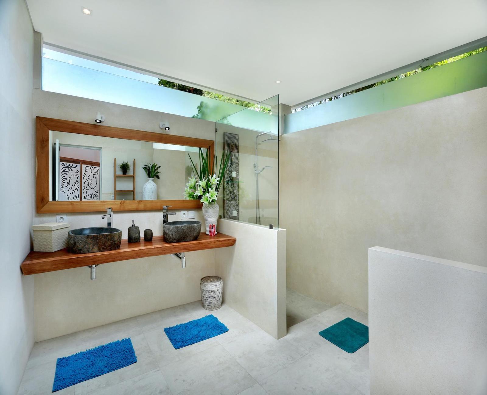 Modern bathroom with double sinks and shower area.