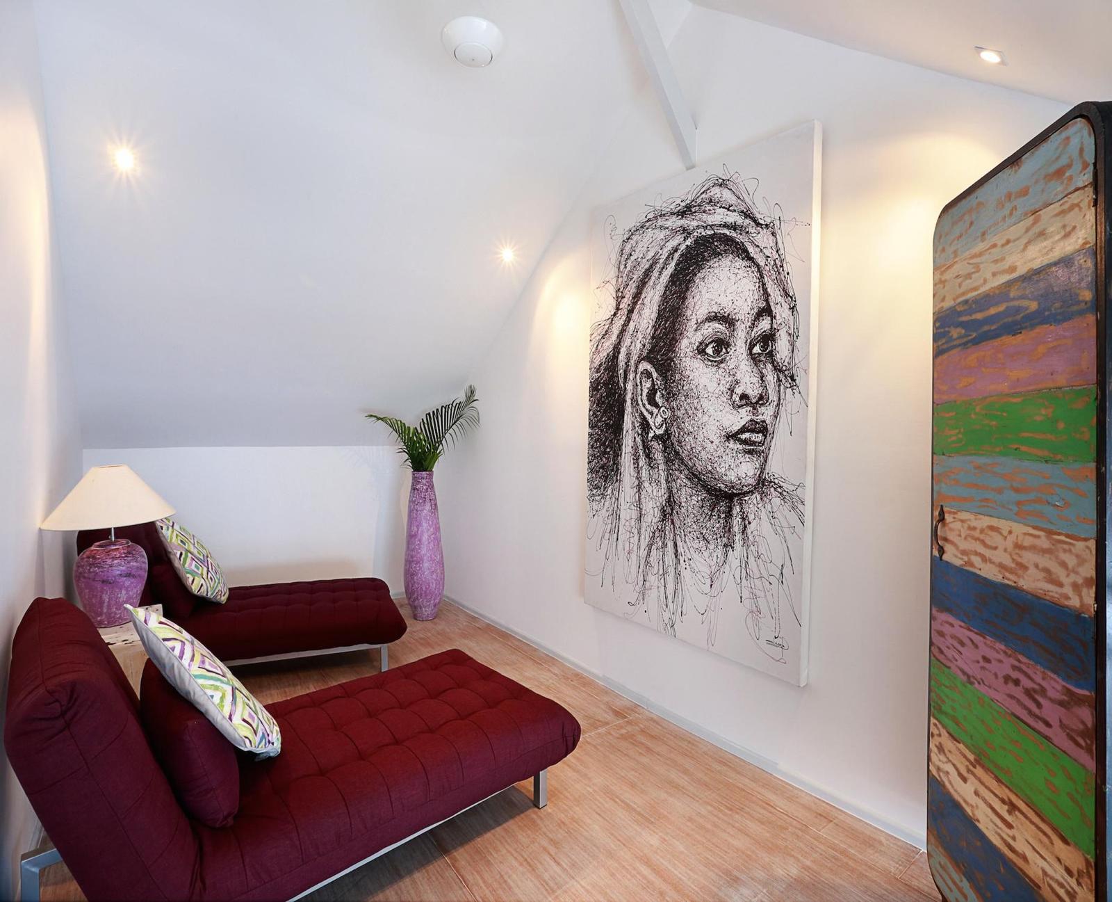Modern room with artwork and maroon chaise lounges.