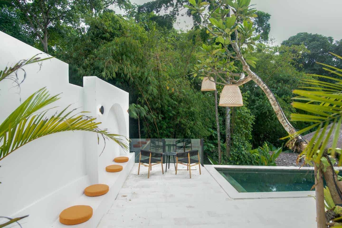 Tropical patio with pool and lush greenery.