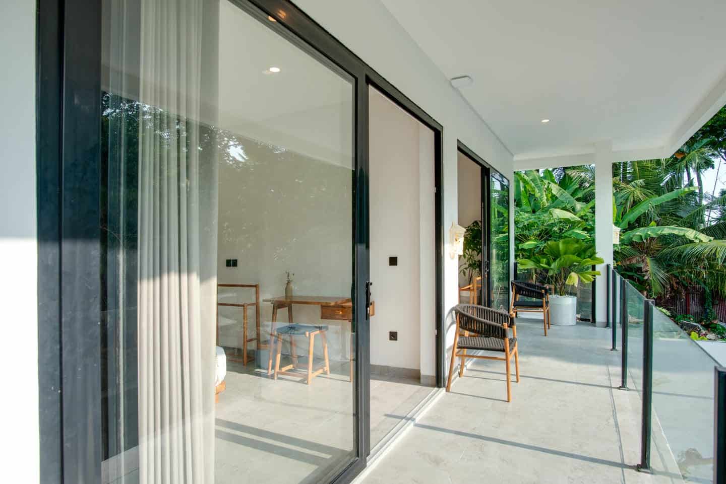 Modern balcony with patio furniture and lush plants.