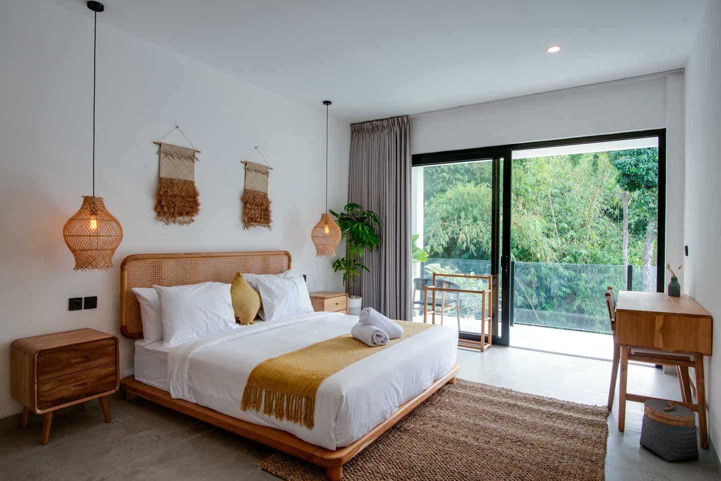 Modern bedroom with large window overlooking greenery.