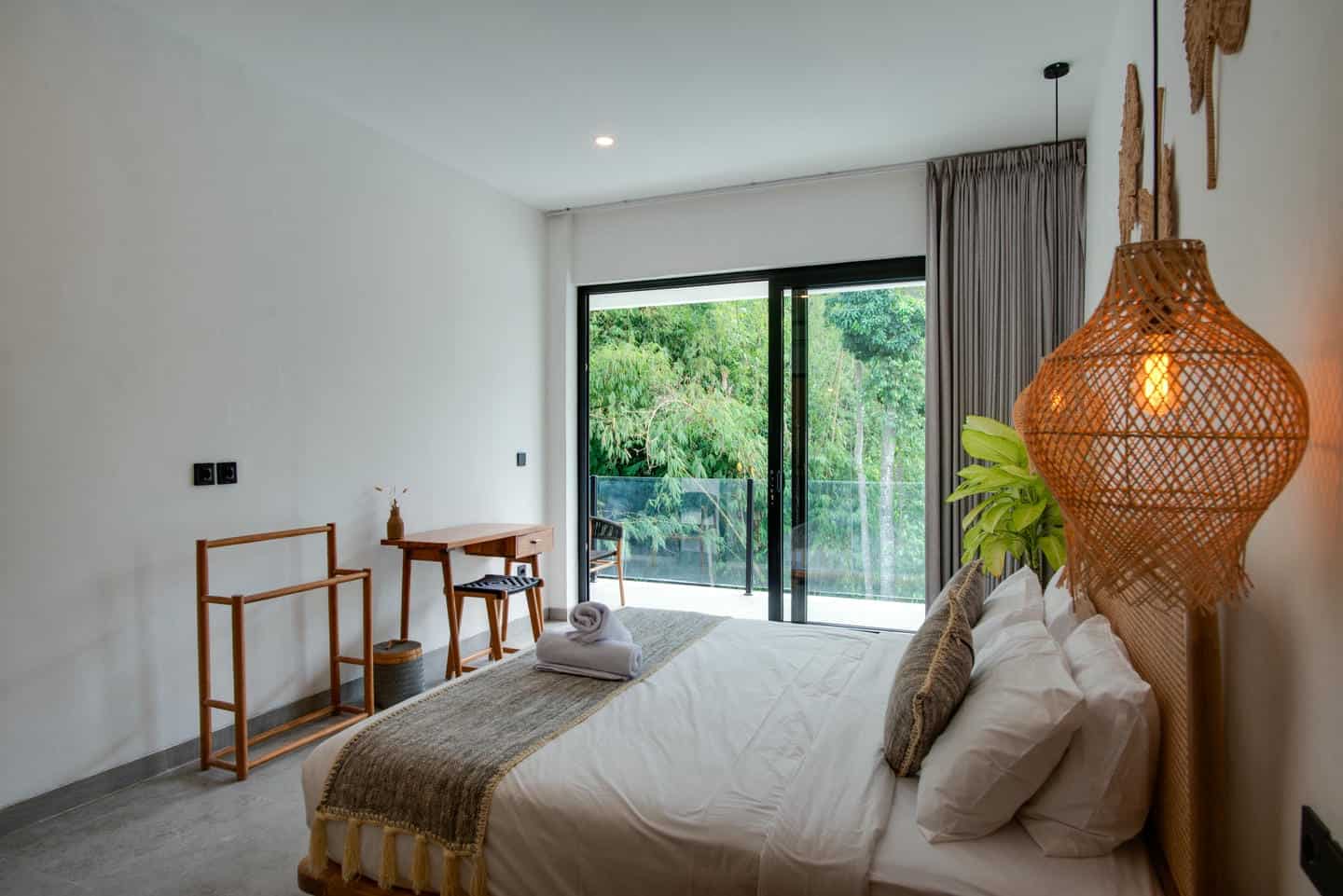 Modern bedroom with plant and large window view.