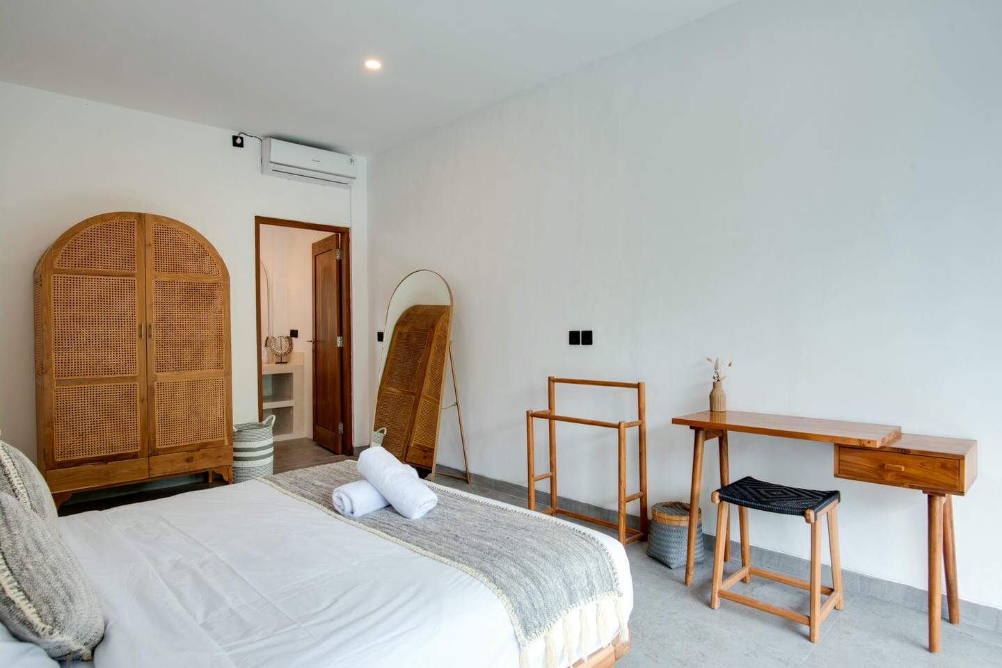 Minimalist bedroom with wooden furniture and white walls.
