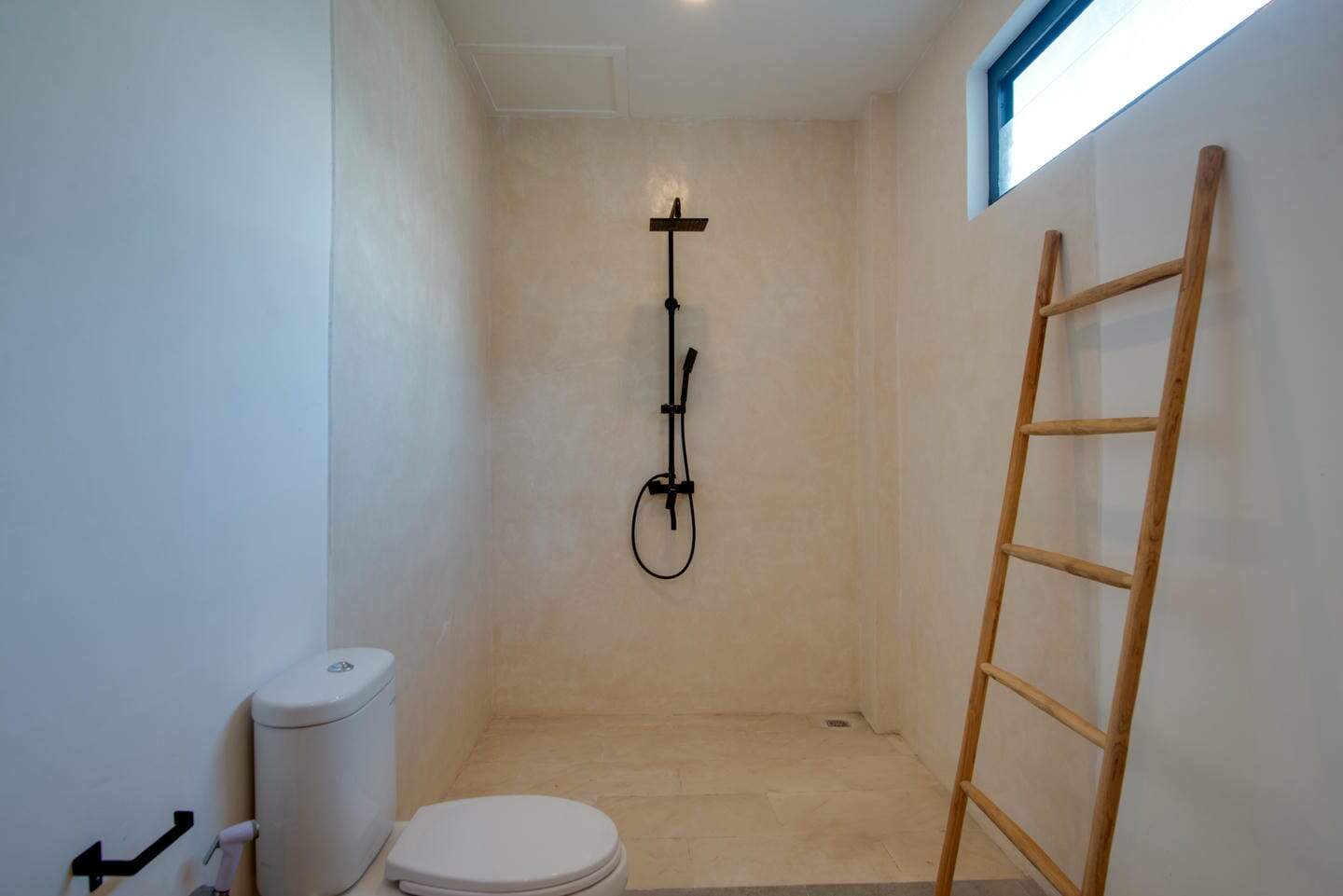 Minimalist bathroom with shower and wooden ladder.