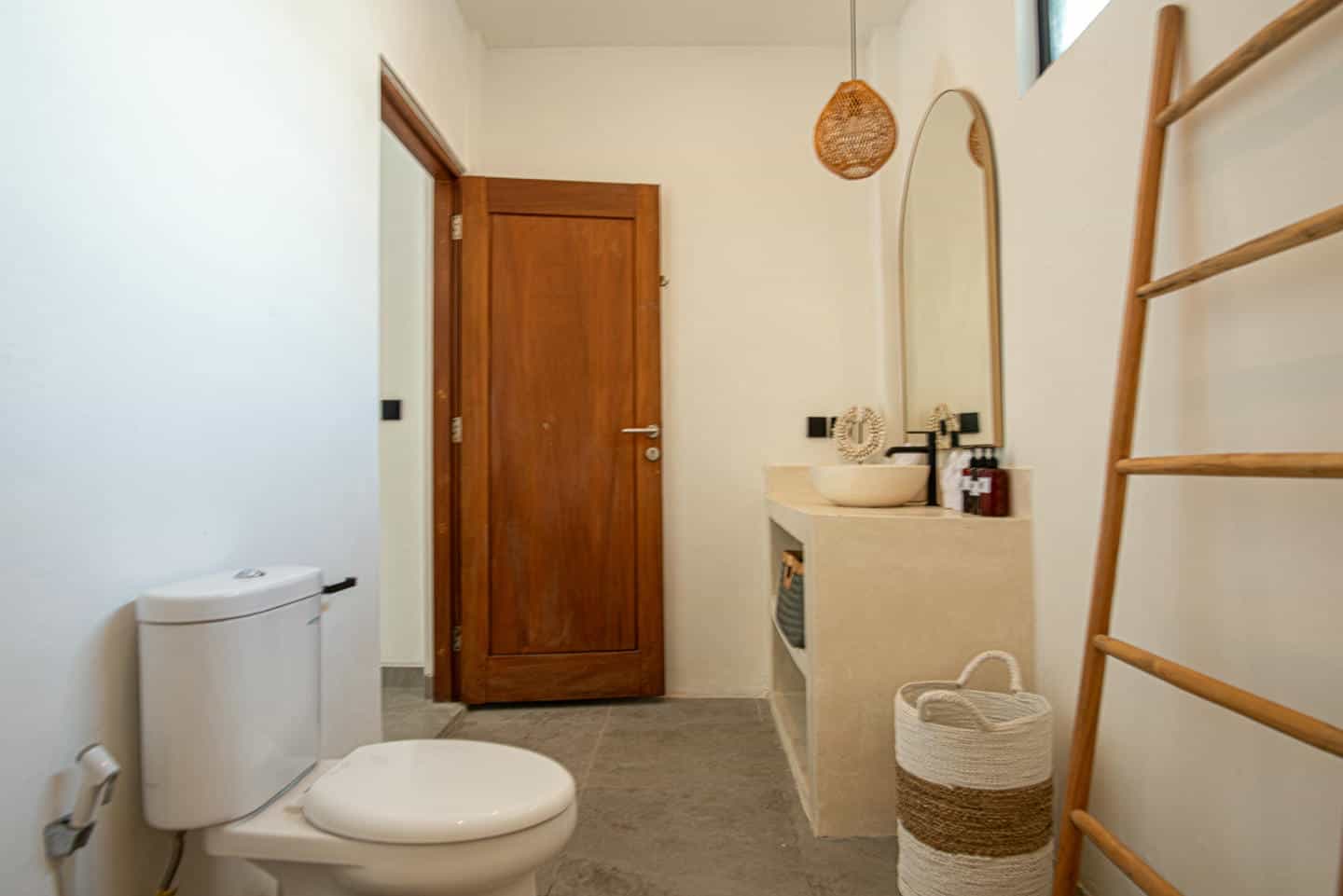 Modern bathroom with wooden accents and ladder shelf.