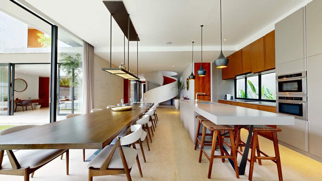 Modern kitchen with long dining table and chairs.