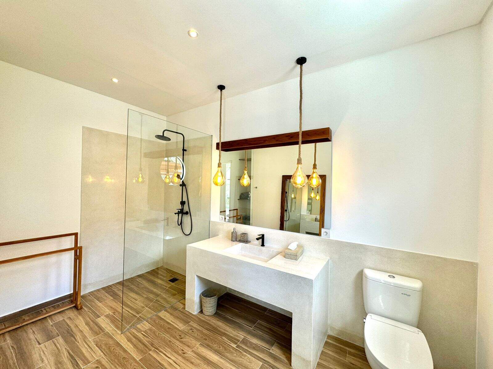 Modern bathroom with glass shower and wooden floor.