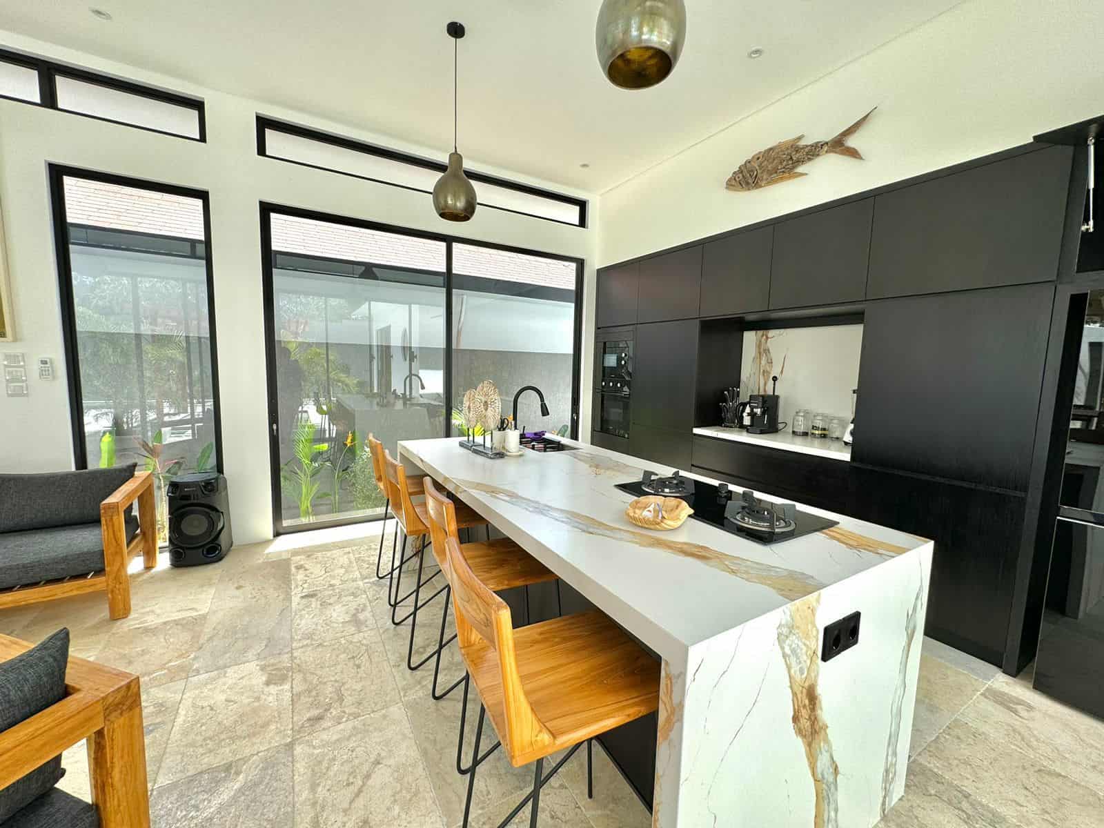 Modern kitchen with marble island and barstools.