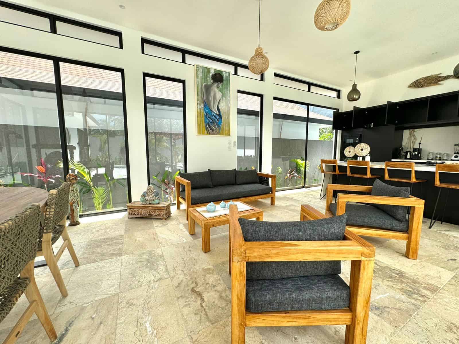 Modern living room with wooden furniture and large windows.
