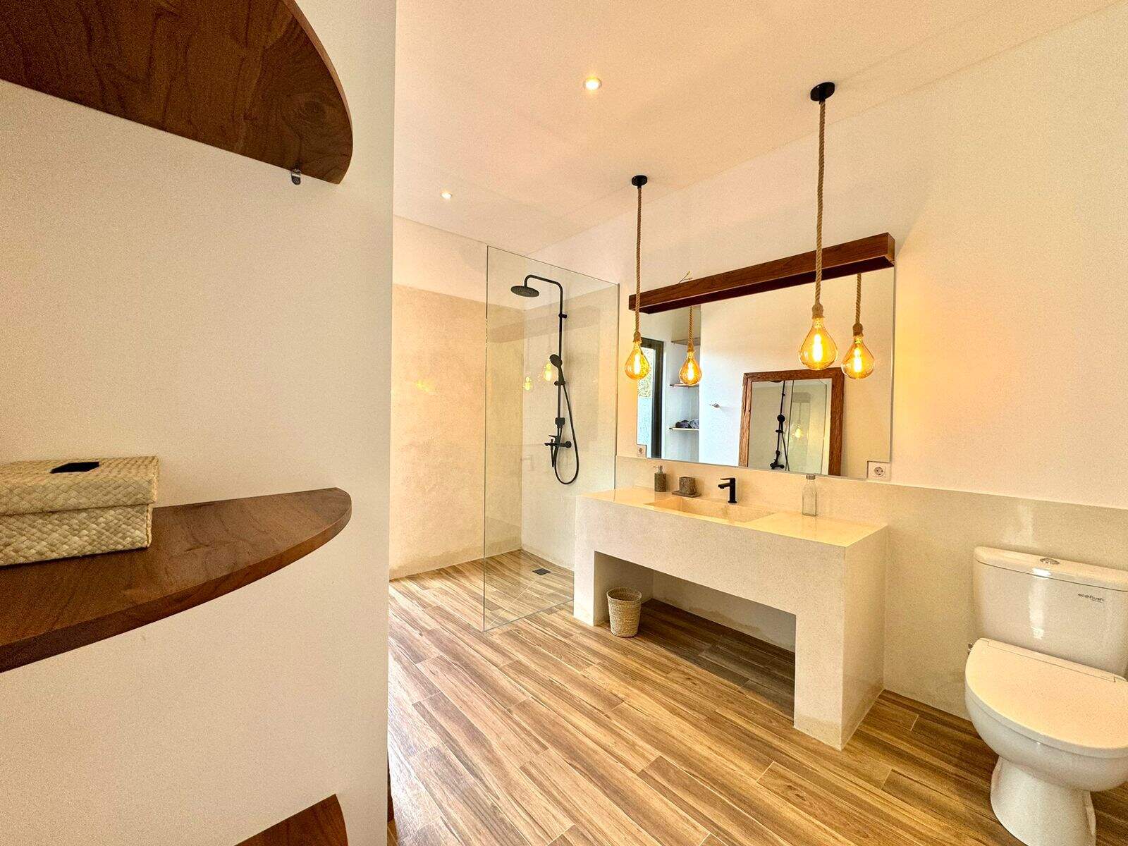 Modern bathroom with wood accents and hanging lights.