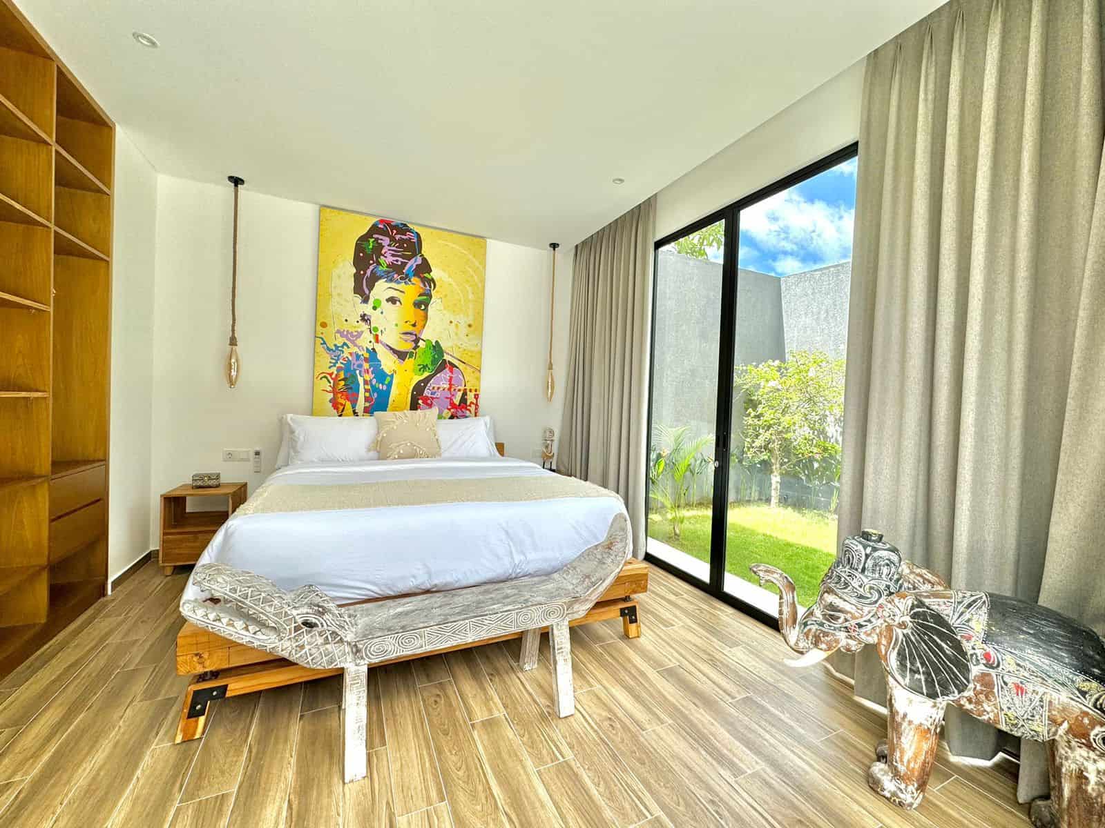 Modern bedroom with colorful artwork and wooden elephant