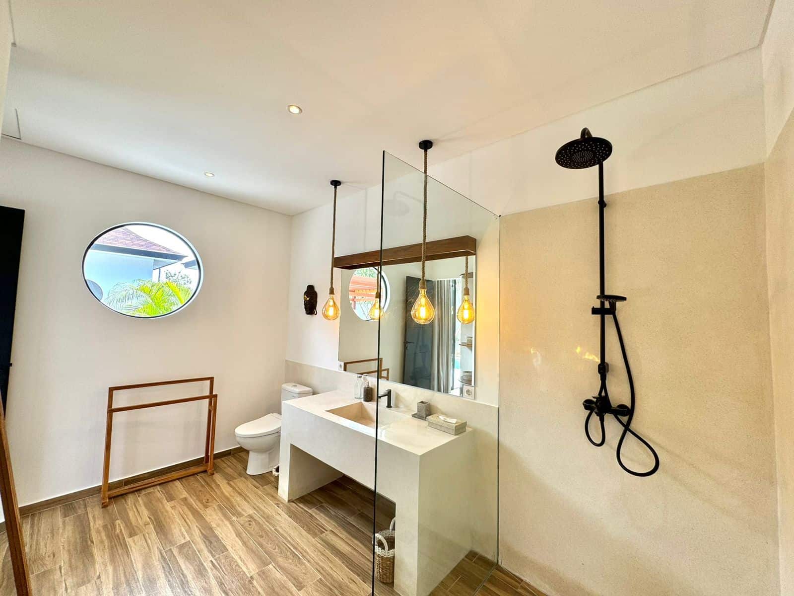 Modern bathroom with glass shower and wooden floor.
