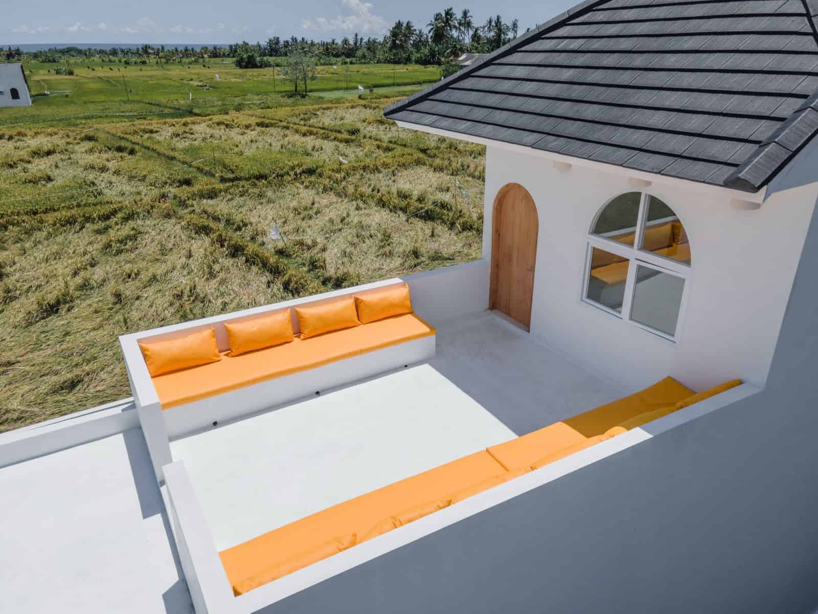 Rooftop patio with orange cushions overlooking fields.
