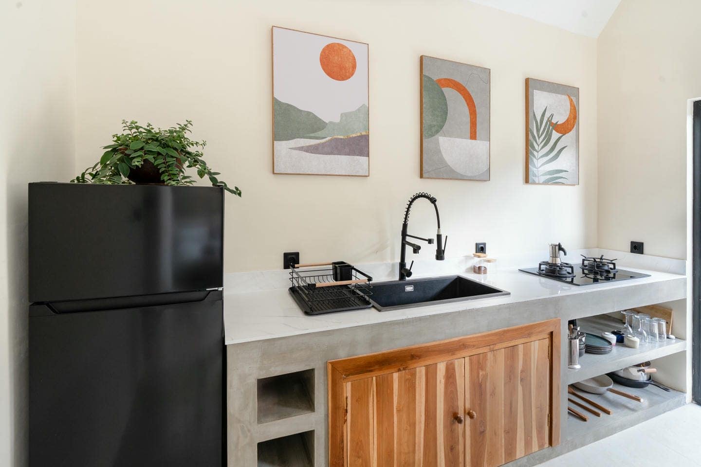 Modern kitchen with black fridge and abstract art.