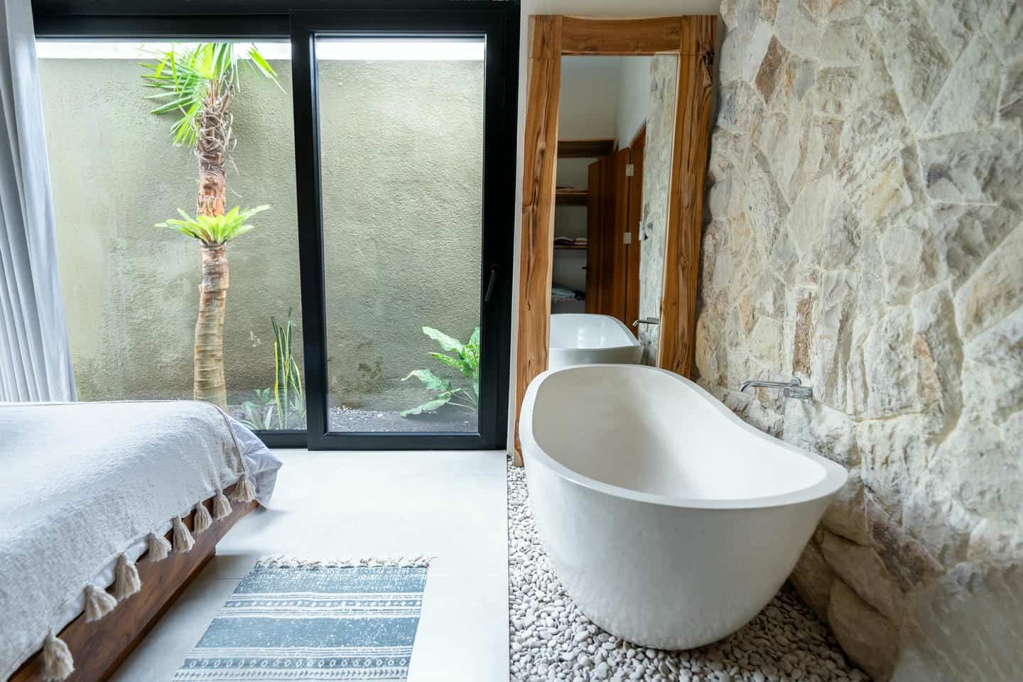 Modern bathroom with freestanding tub and stone wall.