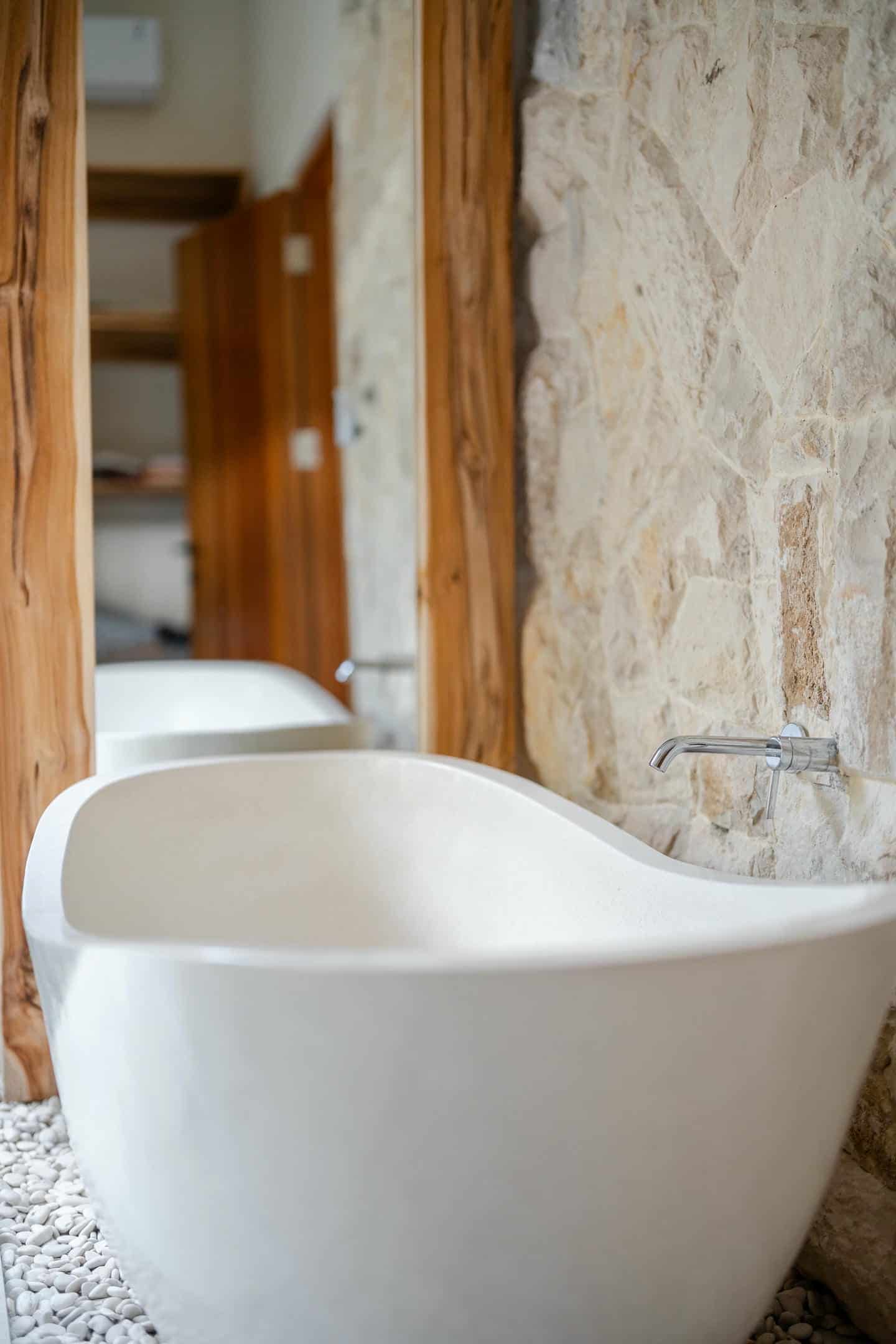 Modern bathroom with freestanding tub and stone wall