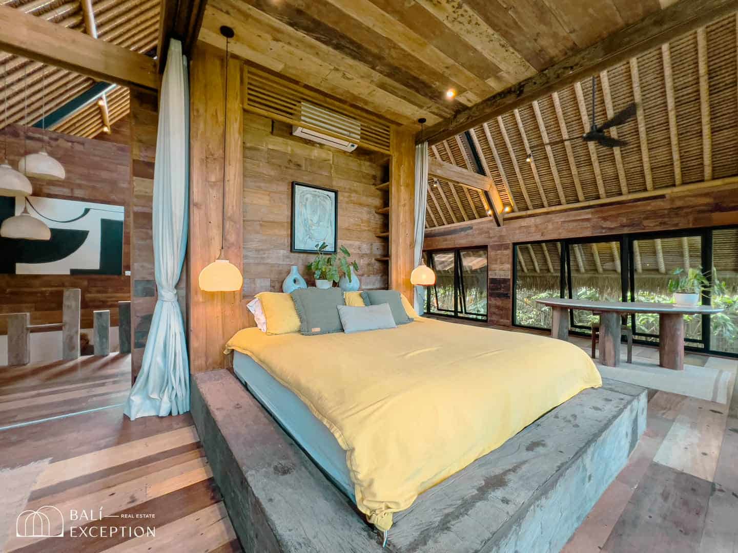 Rustic bedroom with wooden decor and large windows.