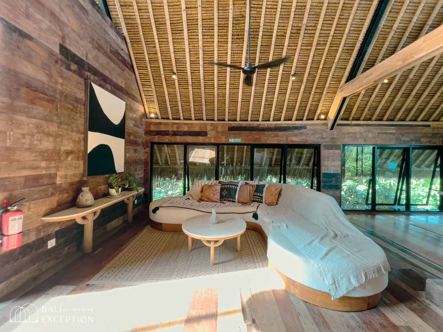 Cozy living room with curved couch and wooden ceiling.