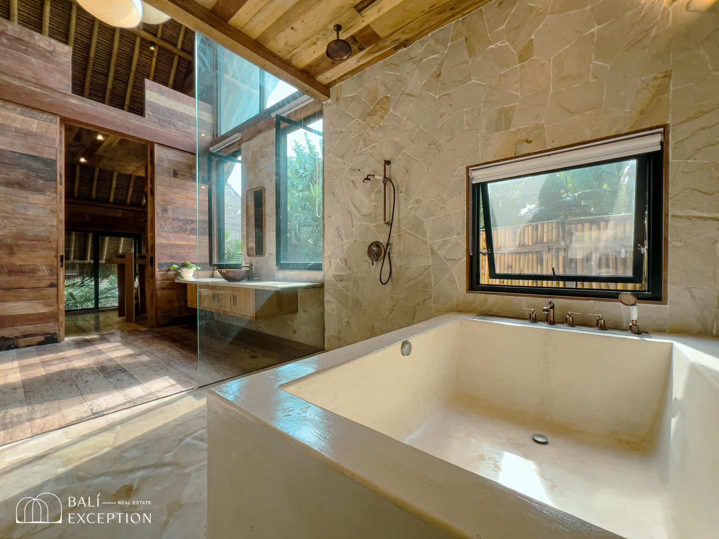 Luxurious tropical bathroom with large tub and window.