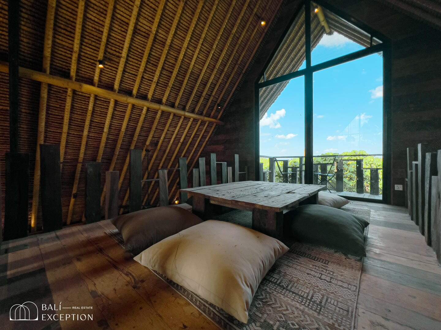 Rustic attic room with large window and cushions.