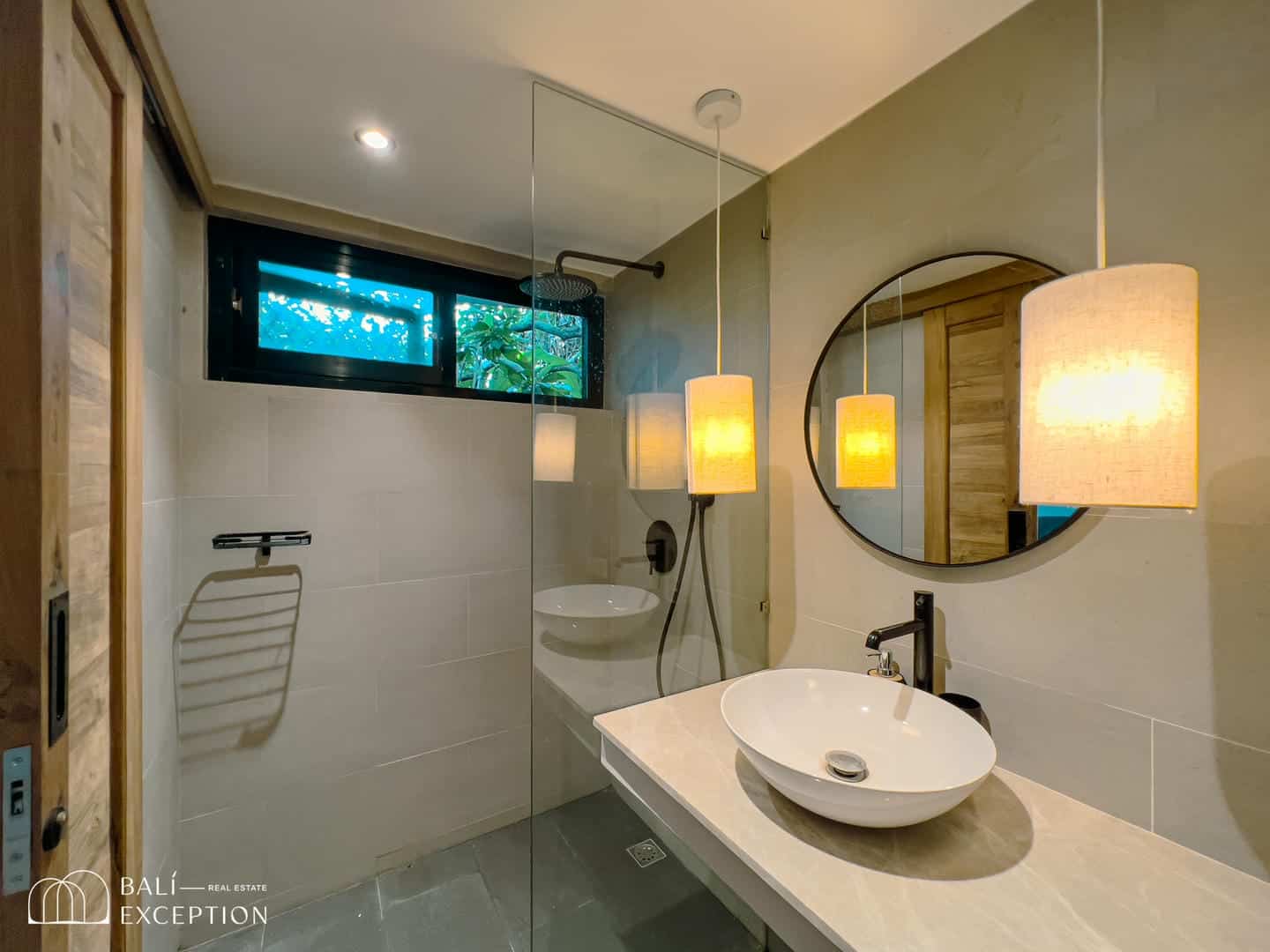 Modern bathroom with round mirror and pendant lights.