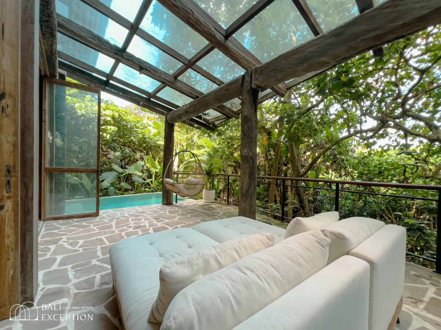 Cozy patio with lush garden and hanging chair.