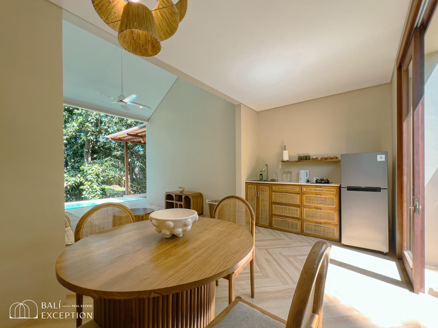 Dining room with wooden table and kitchen view.