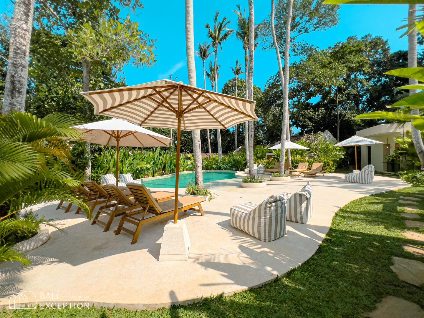 Tropical poolside with lounge chairs and umbrellas.