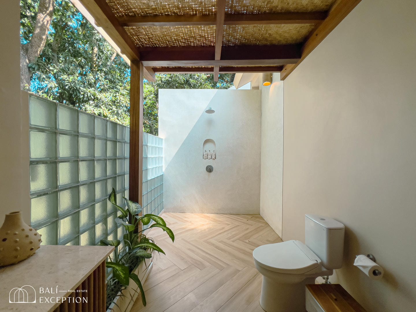 Outdoor bathroom with glass wall and greenery